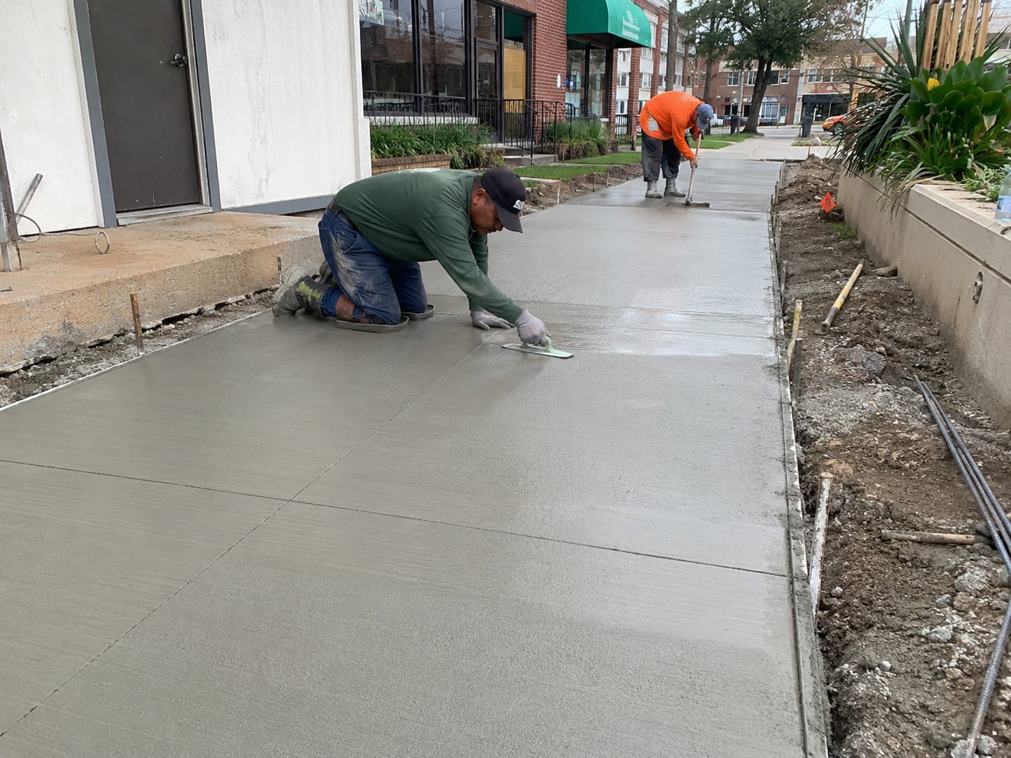 Tradesmen finishing a smooth concrete footpath outside a Perth shopfront